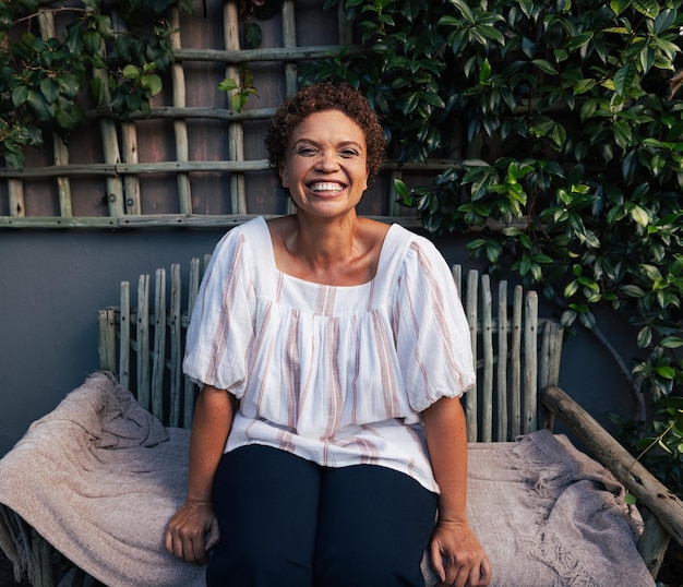 Heureuse femme mûre sur un banc Femme souriante aux cheveux courts se relaxant dans le jardinx9xA