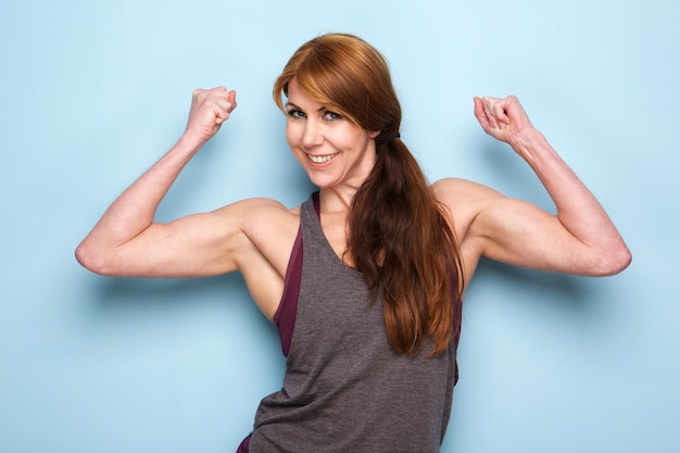 Heureuse femme mûre fléchissant les muscles du biceps