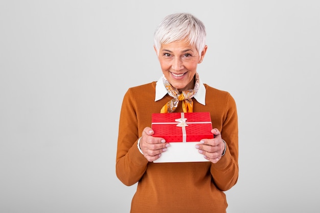 Heureuse femme mûre tenant une boîte-cadeau et en la regardant