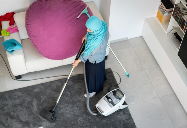 Heureuse femme musulmane nettoyant le salon de la maison moderne. Photo de haute qualité