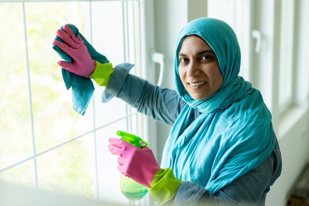 Heureuse femme musulmane nettoyant le salon de la maison moderne. Photo de haute qualité