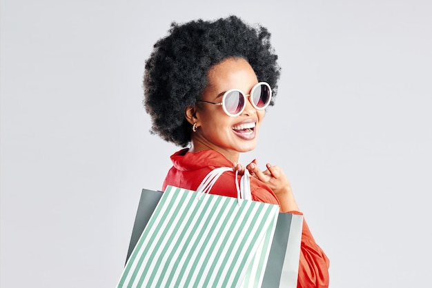 Photo heureuse femme noire afro et sacs à provisions pour vente à prix réduit ou affaire de mode sur un fond de studio blanc