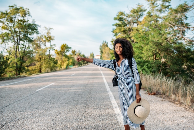 Heureuse Femme Noire Faisant De L'auto-stop Avec Les Pouces Vers Le Haut