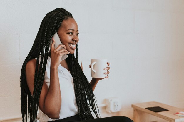 Heureuse femme noire parlant au téléphone au café