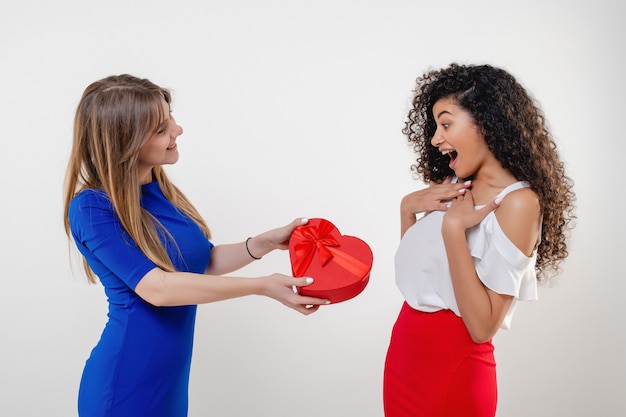 Heureuse femme noire recevant la boîte présente en forme de coeur de la petite amie isolée