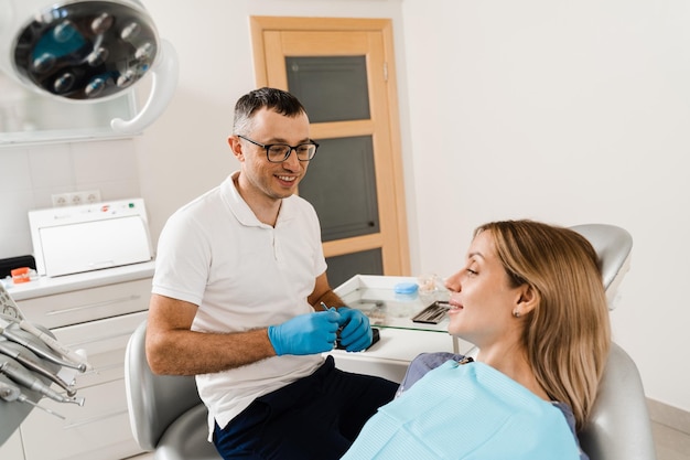 Heureuse femme patiente de la dentisterie Traitement des dents Jolie fille assise dans un cabinet dentaire et souriant Dentiste visite et consultation