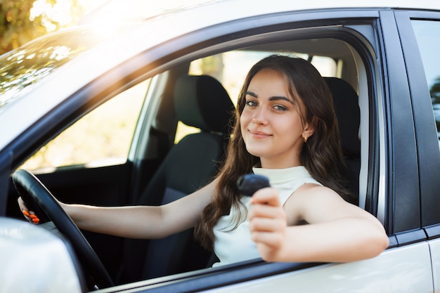 Heureuse femme pilote se vanter de recevoir son permis de conduire, montrant sa clé de voiture et se sentant heureuse et en forme. Jeune étudiante a sa première voiture