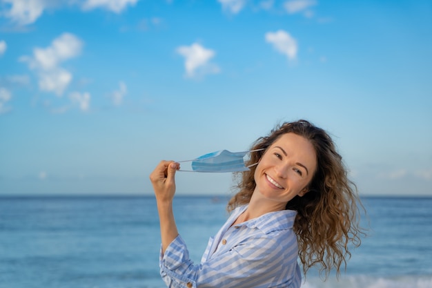 Heureuse Femme Portant Un Masque Médical En Plein Air Sur Fond De Ciel Bleu