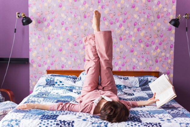 Heureuse femme porte un pyjama et se détendre à la maison et lire un livre.