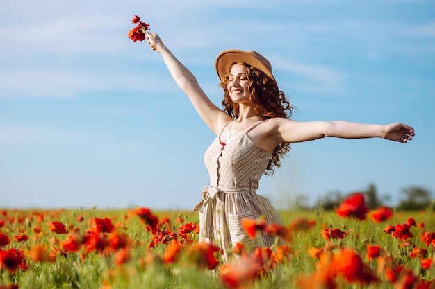 Heureuse femme posant dans un champ de coquelicots