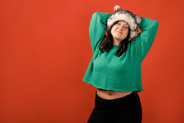 Heureuse femme positive de taille plus. Concept positif de corps heureux. J'aime mon corps. Jolie femme en surpoids posant devant la caméra en studio sur un fond coloré. Fille portant un pull et un chapeau d'hiver