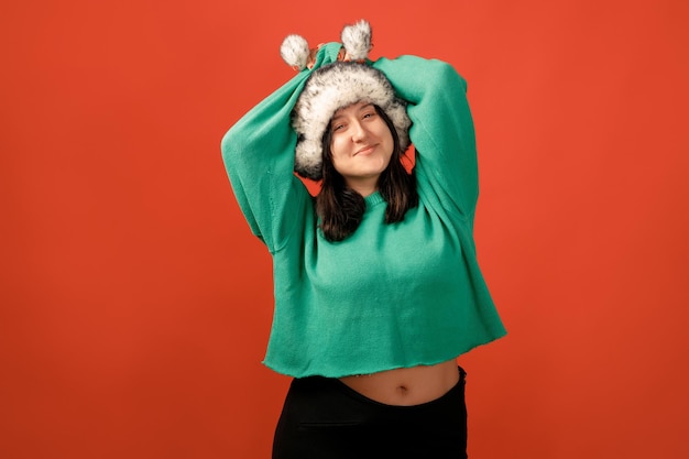 Heureuse femme positive de taille plus. Concept positif de corps heureux. J'aime mon corps. Jolie femme en surpoids posant devant la caméra en studio sur un fond coloré. Fille portant un pull et un chapeau d'hiver