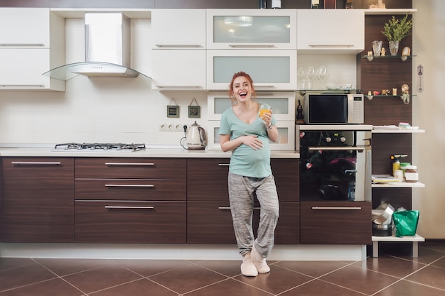 Heureuse femme pregnat loughing sur la cuisine.