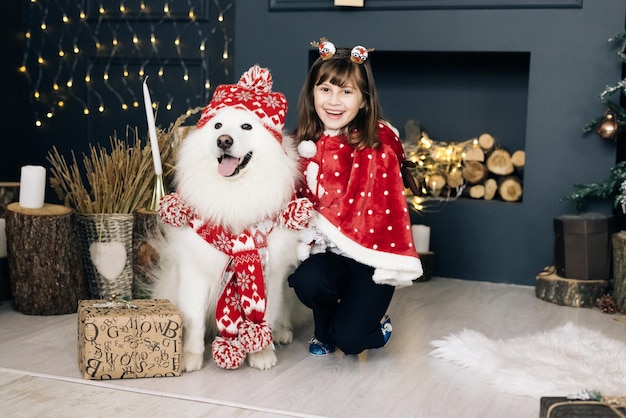 Heureuse femme propriétaire et chien samoyède blanc en hiver petite fille et chien pour noël souriant