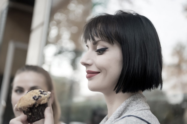 Heureuse femme regarde cupcake à paris, france, nourriture. Femme sensuelle avec gâteau muffin, collation. Nourriture, dessert, collation. Beauté, look, maquillage. Faim, tentation, appétit.