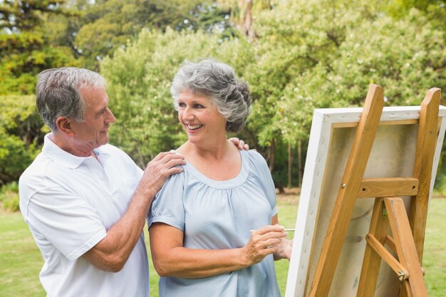Heureuse femme à la retraite, peignant sur toile avec son mari
