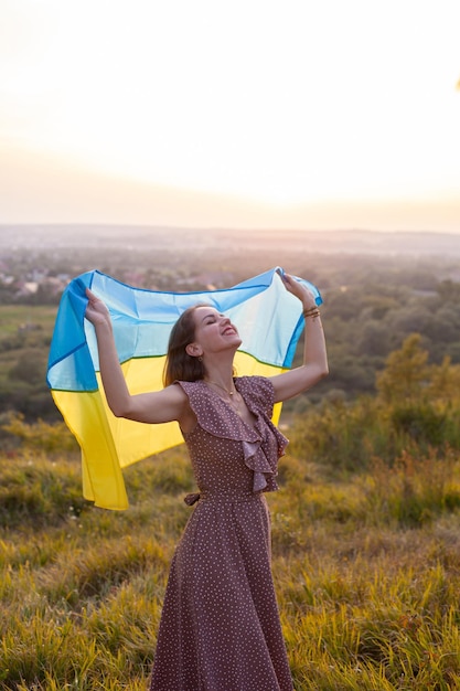 Heureuse femme en robe longue tenant un drapeau jaune et bleu de l'Ukraine