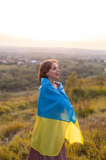 Heureuse femme en robe longue tenant un drapeau jaune et bleu de l'Ukraine