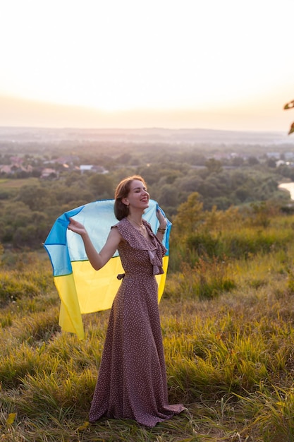 Heureuse femme en robe longue tenant un drapeau jaune et bleu de l'Ukraine