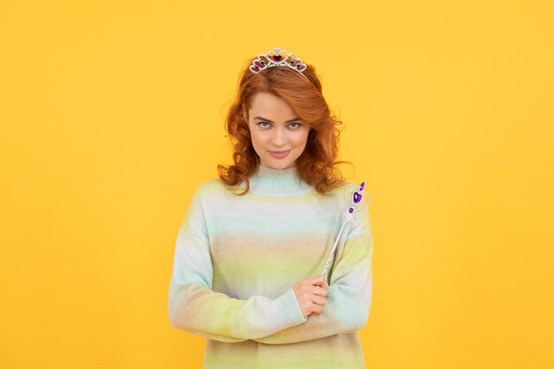 Heureuse femme rousse en couronne de reine avec baguette magique faire voeu