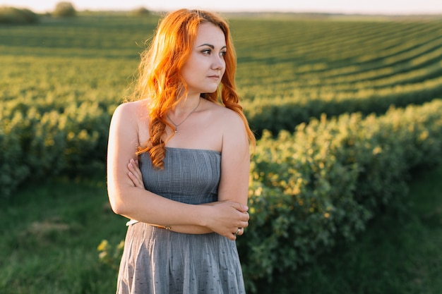 Heureuse femme rousse dans un champ vert