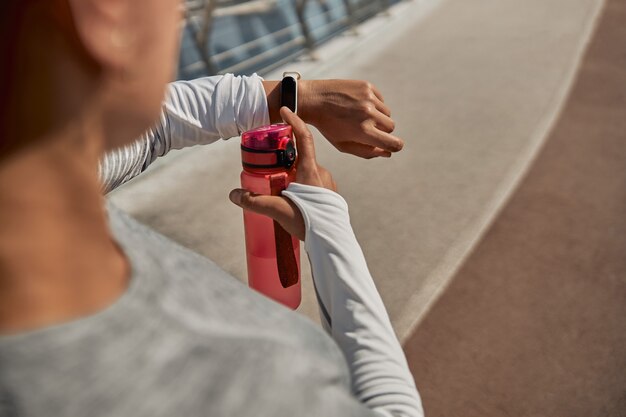 Heureuse femme saine et sportive boit de l'eau après l'entraînement en journée ensoleillée