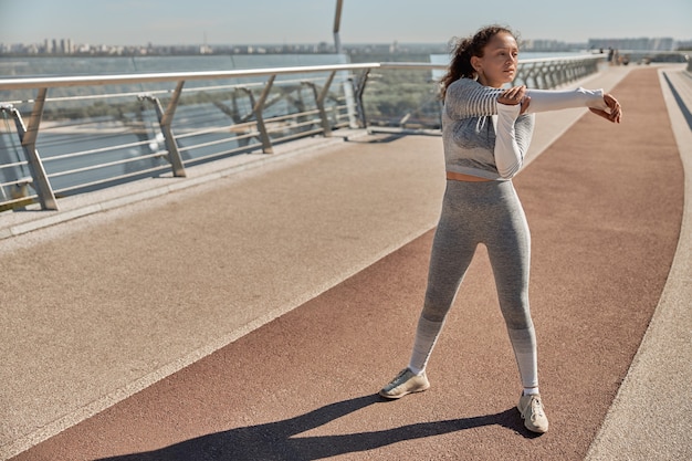 Heureuse femme saine et sportive fait des entraînements en journée ensoleillée