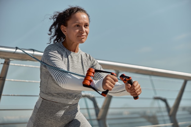 Heureuse femme saine et sportive fait des exercices de harnais en journée ensoleillée