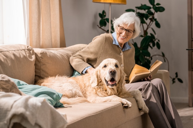 Heureuse femme senior câlins avec chien sur canapé