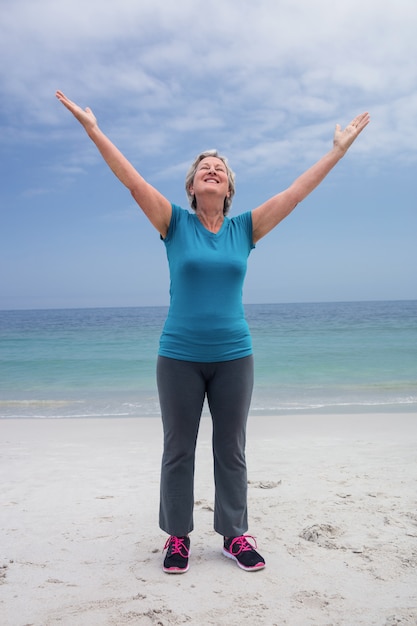 Heureuse femme senior debout sur la plage