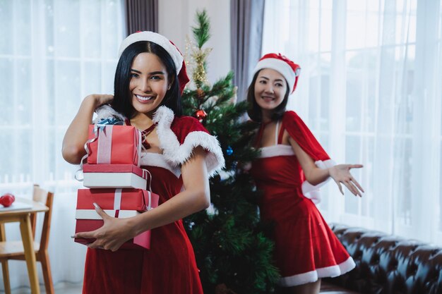 Heureuse femme sexy de santa souriante avec une boîte-cadeau de Noël à la maison.