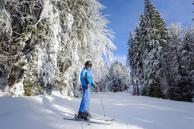 Heureuse femme skieur sur une piste de ski dans la forêt