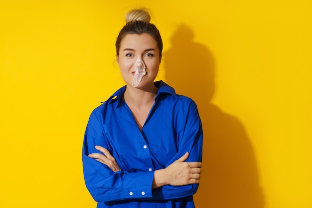 Heureuse femme soufflant une bulle avec du chewing-gum sur fond jaune