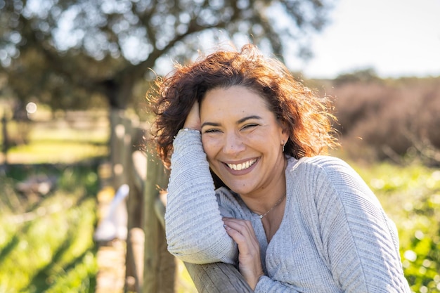 Heureuse femme souriant à la caméra dans un champ lors d'une journée de printemps ensoleillée