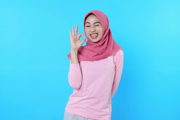 Heureuse femme souriante avec une apparence attrayante et portant le hijab, t-shirt rose montrant dire d'accord sourire bonne humeur