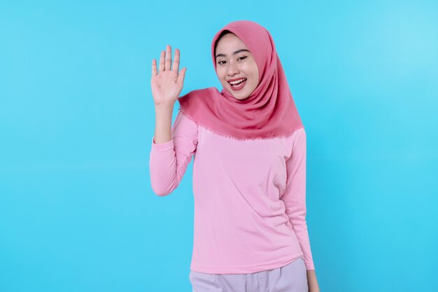 Heureuse femme souriante avec une apparence attrayante et portant un t-shirt rose hijab montrant le sourire