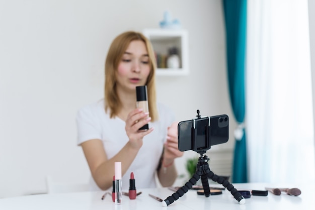 Heureuse femme souriante beauté vidéo blogueur enregistrement maquillage tutoriel à la maison pour son blog vidéo