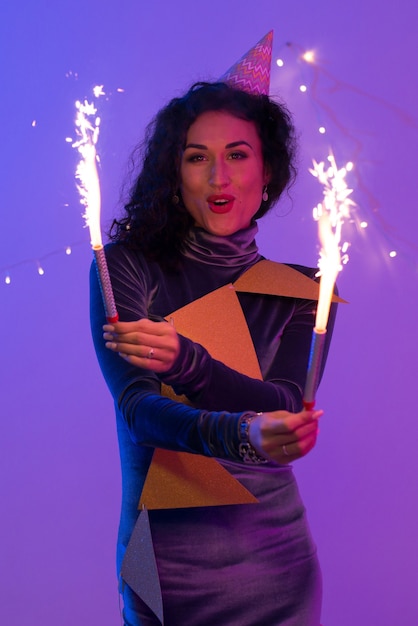 Heureuse femme souriante célébrant avec des feux d'artifice. Fête du nouvel an.