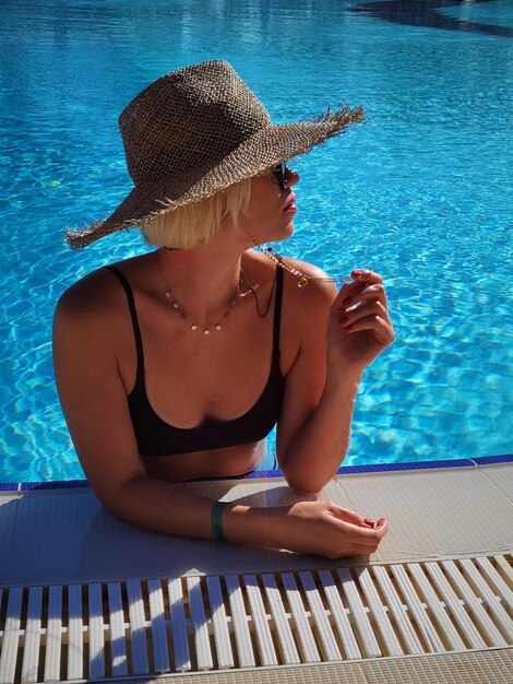 Heureuse femme souriante avec chapeau de paille dans la piscine