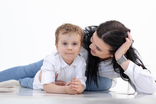 Heureuse femme souriante et garçon allongé sur le sol fond blanc étreignant parler l'autisme de la parentalité attentionnée