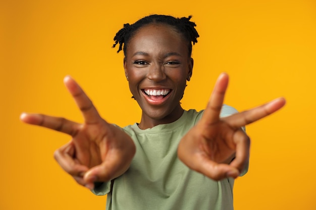 Heureuse femme souriante noire montrant le signe v au studio