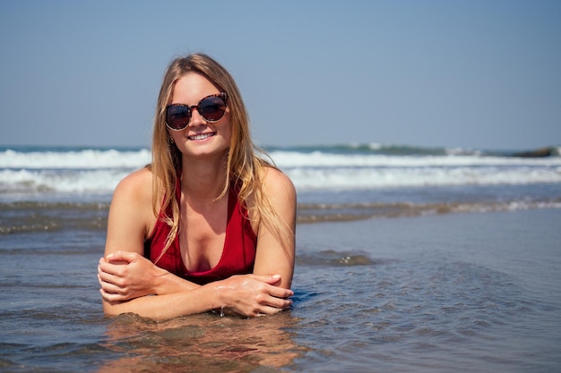 Heureuse femme souriante et s'amusant à la plage Portrait d'été d'une jeune belle fille en bikini rouge