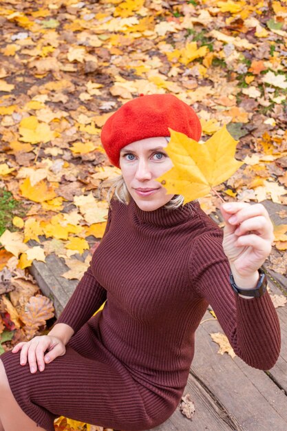 Photo heureuse femme souriante tenant dans ses mains des feuilles d'érable jaune