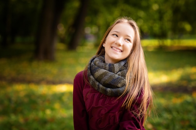 Heureuse femme souriante tenant dans ses mains des feuilles d'érable jaunes sur fond d'automne