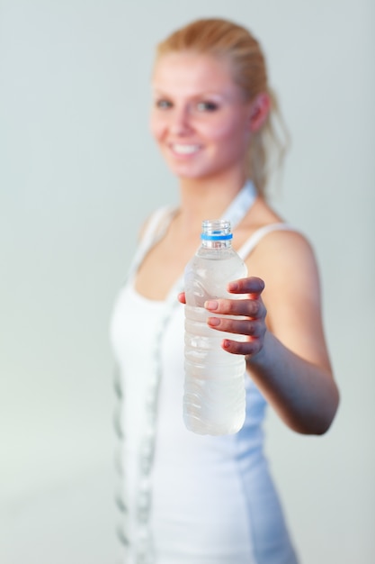 Heureuse femme tenant une bouteille d&#39;eau en mettant l&#39;accent sur l&#39;eau