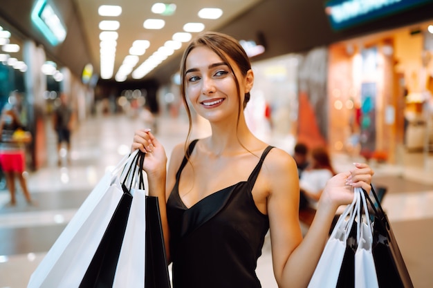 Heureuse femme tenant des sacs à provisions et souriant au centre commercial