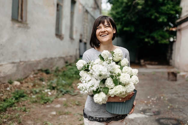 Heureuse femme tenant un seau avec des fleurs blanches de saison