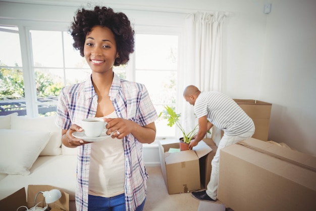 Heureuse femme tenant une tasse dans le salon