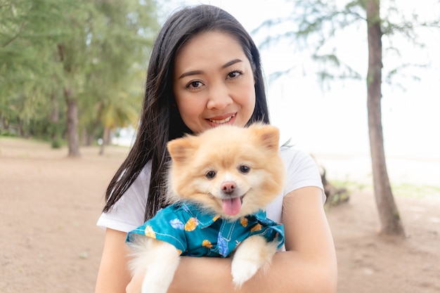 Heureuse femme tient un chien poméranien.