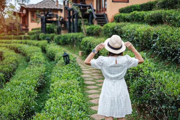 Heureuse femme touristique en robe blanche profiter du beau jardin de thé.